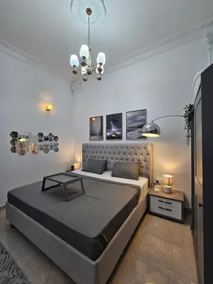 a bedroom with a large bed and a chandelier at Elegant Grey Studio Room with Free Parking and Gaming in Dubai