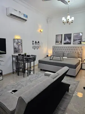 a living room with a bed and a table at Elegant Grey Studio Room with Free Parking and Gaming in Dubai