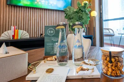 a table with two bottles and a vase with flowers at Boutique 3BR in JBR Upgraded by UDH in Dubai