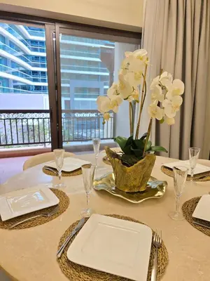 a table with a plate and a vase of white flowers at Fairmont North Residences Palm Jumeirah in Dubai