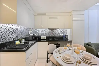 a kitchen with a table and chairs and a kitchen with white cabinets at DAMAC Maison Aykon City Dubai in Dubai