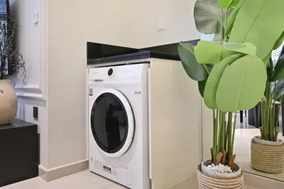 a washing machine in a room with a plant at DAMAC Maison Aykon City Dubai in Dubai