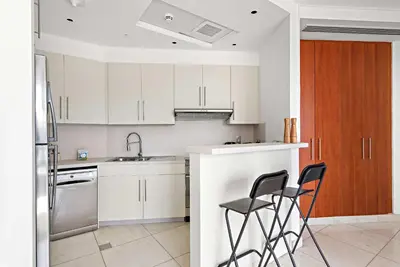 a kitchen with white cabinets and black chairs in it at Silkhaus Modern Studio in Central Park Tower DIFC in Dubai