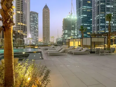 a row of white lounge chairs in a city at FIRST CLASS Studio Relaxing Canal View in Dubai