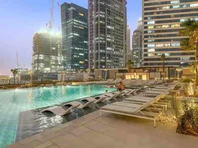 a large swimming pool with lounge chairs in a city at FIRST CLASS Studio Relaxing Canal View in Dubai