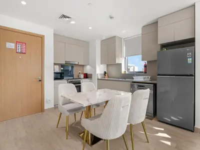 a kitchen with a table and chairs and a refrigerator at The Royal Suite 1 BDR in Sunset-02 in Dubai