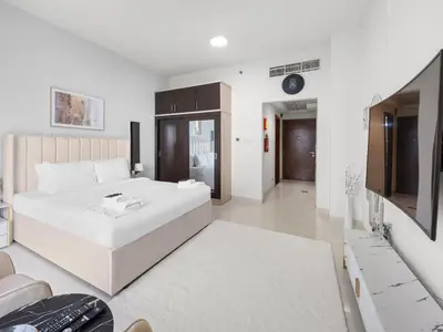 a white bedroom with a large white bed and a couch at Modern Comfort City Studio In Al Manara 04 in Dubai
