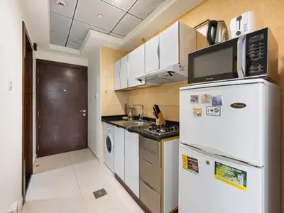 a kitchen with a white refrigerator and a microwave at Modern Comfort City Studio In Al Manara 04 in Dubai