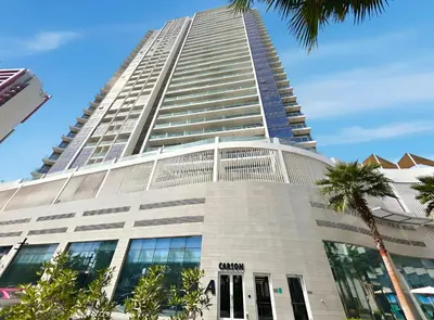 a tall building with palm trees in front of it at Stylish Studio with Balcony in Carson Tower, DAMAC Hills in Dubai