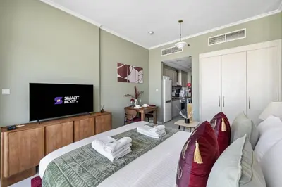 a bedroom with a bed with a flat screen tv at Stylish Studio with Balcony in Carson Tower, DAMAC Hills in Dubai