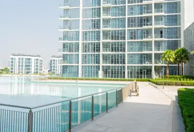 a swimming pool in front of a large building at Beautiful Large 1BR Apt in District 1, MBR Minutes to Downtown in Dubai