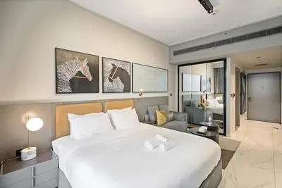 a bedroom with a large white bed and a living room at Chic Getaway with Downtown View, Walk to Dubai Mall and Burj in Dubai