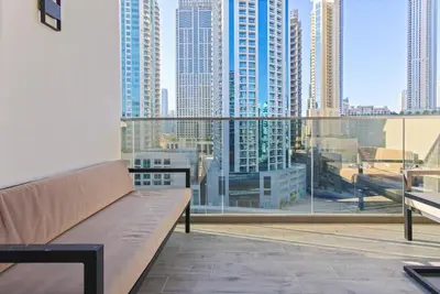 a couch on a balcony with a view of a city at Chic Getaway with Downtown View, Walk to Dubai Mall and Burj in Dubai