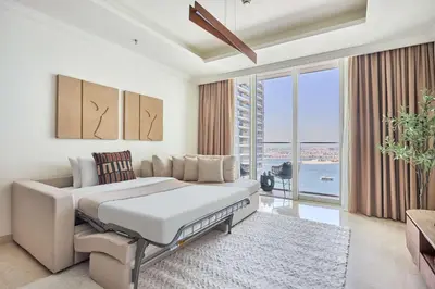 a white bedroom with a bed and a large window at Frank Porter - Palace Beach Residence in Dubai