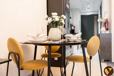 a dining room table with chairs and a vase of flowers at Vogue Elite Business Bay Residence Close to Burj Khalifa and Dubai Mall, Studio Apartment with Balcony, City and Canal View, Access to all Amenities in Dubai