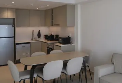 a kitchen with a wooden table and white chairs at Luxury 1BR Retreat with Dubai Marina views by Crescent Key in Dubai
