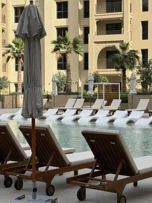 a row of lounge chairs and an umbrella next to a pool at Elegant 1BR with Skyline View Bright & Modern by Crescent Key in Dubai