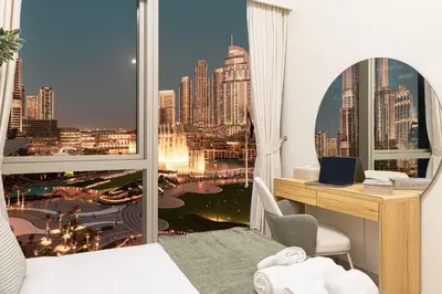 a bedroom with a desk and a view of a city at INCREDIBLE BURJ KHALIFA & DUBAI FOUNTAIN Views - 2 BR Luxury Apartment - Sanctuary Stays in Dubai