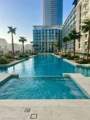 a large swimming pool with palm trees and buildings at Elegant Dubai Stay Pool, Gym, Padel & Concierge in Dubai