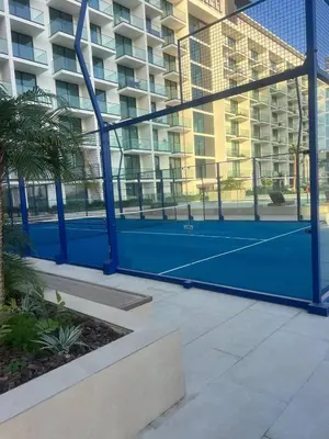 a blue tennis court in front of a building at Elegant Dubai Stay Pool, Gym, Padel & Concierge in Dubai