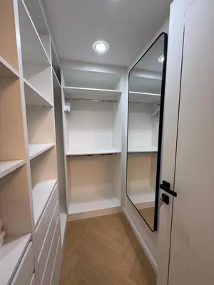 a walk in closet with white shelves and a mirror at Yansoon 4 , Old Town Downtown in Dubai