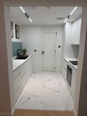 a kitchen with white cabinets and a marble floor at Yansoon 4 , Old Town Downtown in Dubai