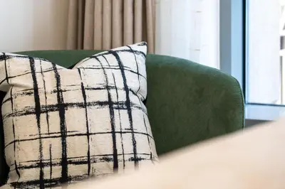 a pillow on a green couch next to a window at Burj Khalifa View 29 Boulevard Downtown - Free Parking in Dubai