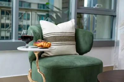 a green chair with a plate of food and a glass of wine at Burj Khalifa View 29 Boulevard Downtown - Free Parking in Dubai