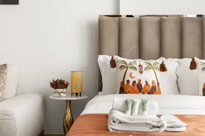 a bedroom with a white bed with a palm tree pillow at Chic Studio with Balcony & Pool in Oxford Gardens in Dubai