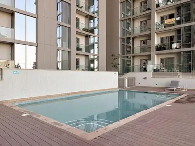 a swimming pool in front of a tall building at FIRST CLASS 1BR Urban Serenity Near Downtown in Dubai