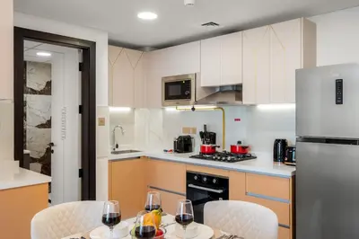 a kitchen with a table and chairs and a refrigerator at FIRST CLASS 1BR Miracle Garden View Skyz Arjan in Dubai