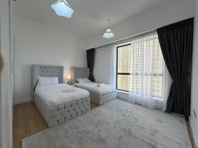 a white bedroom with two beds and a window at 2BR Apartment in JBR The Walk in Dubai