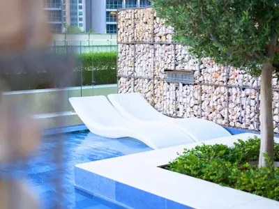 a white bench in front of a stone wall at Business Bay Luxury Apt - 5min Burj Khalifa, Mall & Metro in Dubai