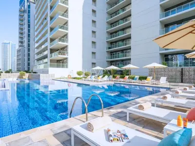 a swimming pool with lounge chairs and a hotel at Business Bay Luxury Apt - 5min Burj Khalifa, Mall & Metro in Dubai