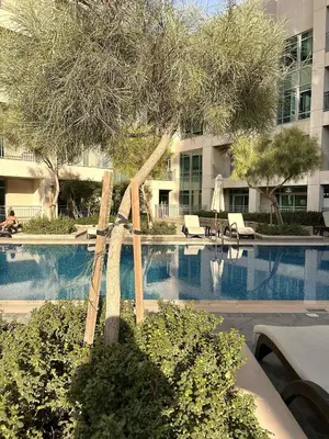 a swimming pool with a tree in front of a building at Premium Downtown 1BD Apartment Burj Khalifa View 9 Mins walk Dubai Mall in Dubai