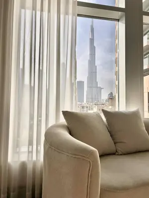 a couch in front of a window with a view of a city at Premium Downtown 1BD Apartment Burj Khalifa View 9 Mins walk Dubai Mall in Dubai