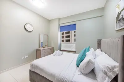 a bedroom with a bed and a clock on the wall at FiveX Premium 4BR Beachfront Living at JBR in Dubai