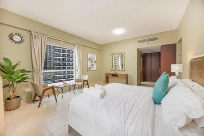 a bedroom with a large bed and a living room at FiveX Premium 4BR Beachfront Living at JBR in Dubai
