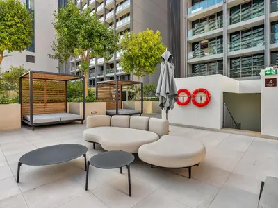 a patio with tables and chairs and an umbrella at Cozy modern STUDIO in STERLING DOWNTOWN I DUBAI MALL I Sleeps 4 in Dubai