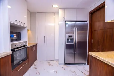 a kitchen with a stainless steel refrigerator and wooden cabinets at Luxury 3 BR Premium Feel Iconic Burj View Connected To Dubai Mall in Dubai