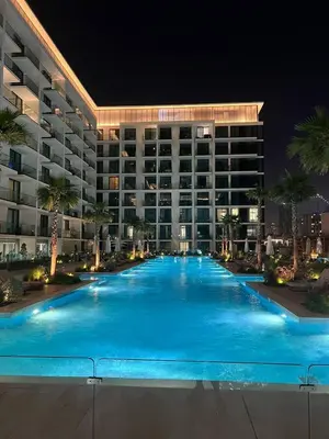 a large swimming pool in front of a building at night at Stylish Dubai Stay, Pool, Padel, Gym, Concierge in Dubai