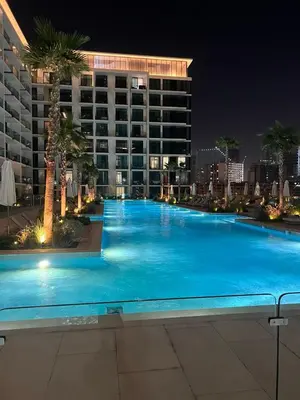 a large swimming pool at night with a large building at Stylish Dubai Stay, Pool, Padel, Gym, Concierge in Dubai