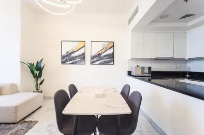 a white living room with a table and chairs at Elite LUX Holiday Homes - Stylish 1BR Living in Amna Tower, Al Habtoor City in Dubai