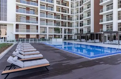 a swimming pool with lounge chairs and a building at Elite LUX Holiday Homes - Stylish Studio at Jewelz by Danube, Dubai in Dubai