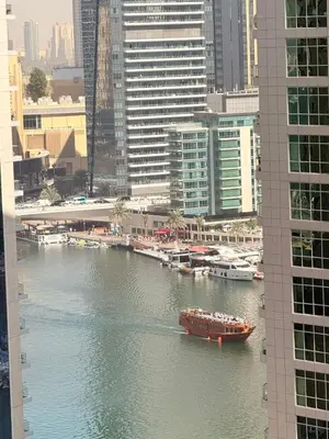 a boat in a river in a city with buildings at Spacious & classic Apartment in center of JBR in Dubai