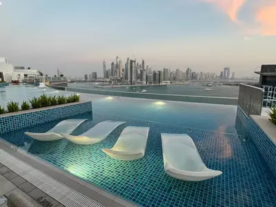 a swimming pool with white chairs and a city skyline at Cozy Studio with Private Beach in Dubai