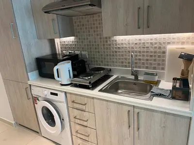 a small kitchen with a sink and a microwave at Cozy Studio with Private Beach in Dubai