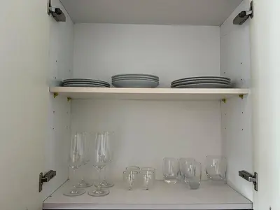 a row of glasses on a shelf with plates at Next to Marina Mall, Close to beach and Metro in Dubai