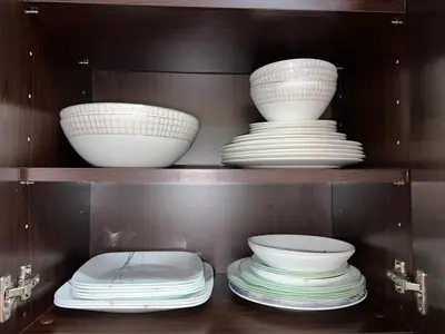 a shelf with bowls and plates in a cabinet at Private beach, Close to Shopping Mall in Dubai