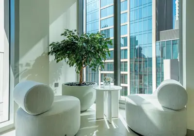 a living room with two chairs and a potted tree in a window at Forte Luxury 2BR Apartment with Skyline City Views near Dubai Mall in Dubai